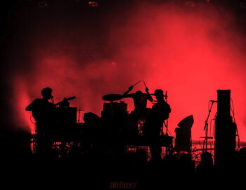 Photo des 3 musiciens sur scène en clair obscur sur fond de lumière rouge