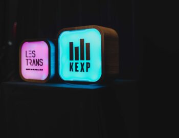 Deux lampes allumées avec les logos "Les trans" et "KEXP"