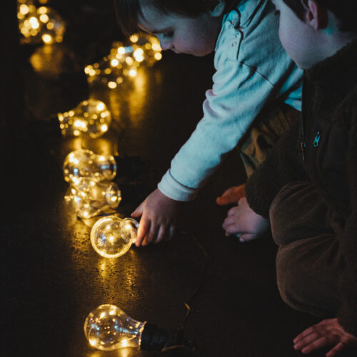 Un enfant touche une ampoule de la guirlande lumineuse posée au sol