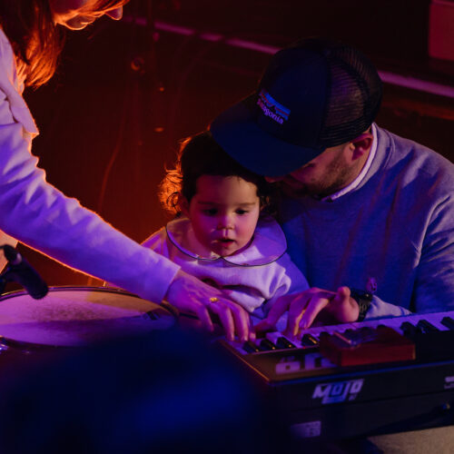 Un couple fait manipuler un instrument clavier à une enfant en bas âge à l'air subjugué