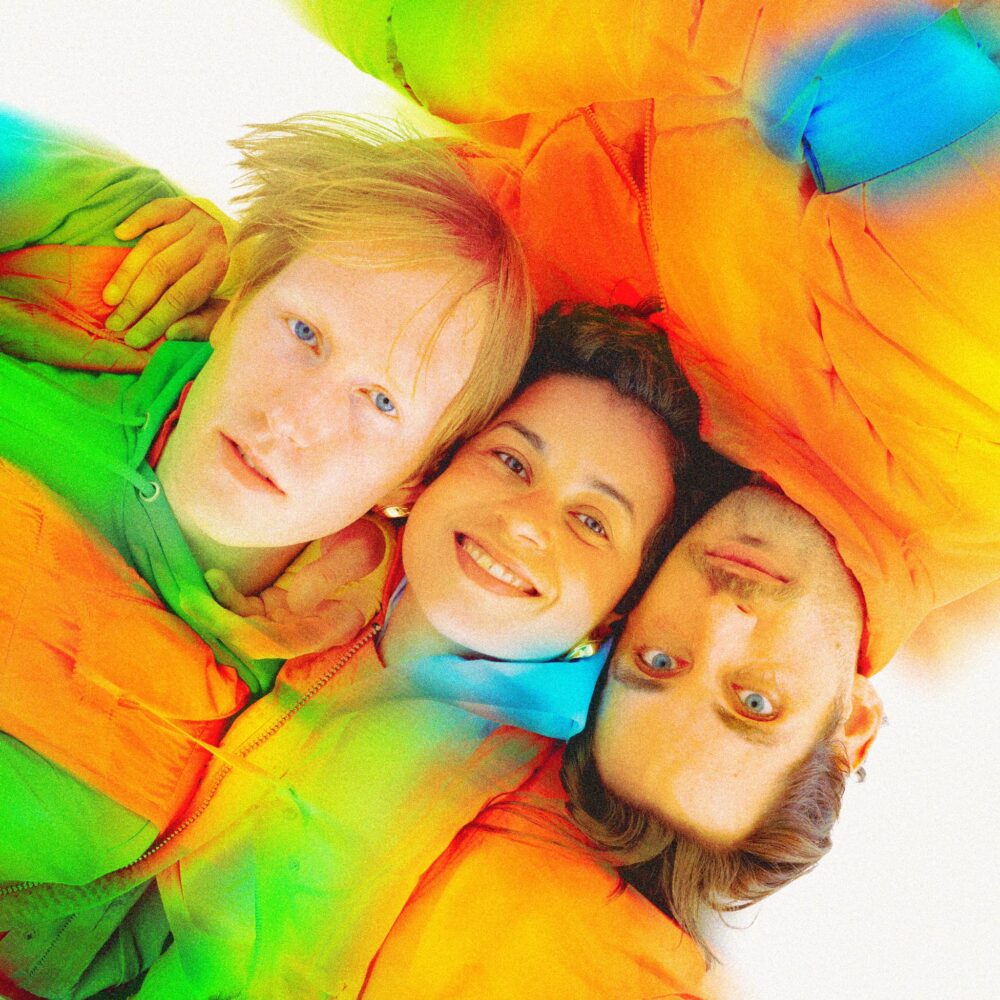 Portrait avec le visage de trois personnes allongées vues d'en haut, habillées en doudounes oranges