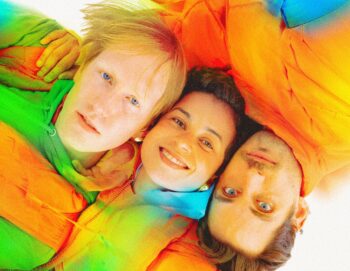 Portrait avec le visage de trois personnes allongées vues d'en haut, habillées en doudounes oranges
