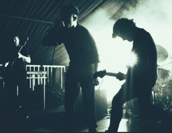 Photo en noir et blanc d'un groupe sur scène en contre jour