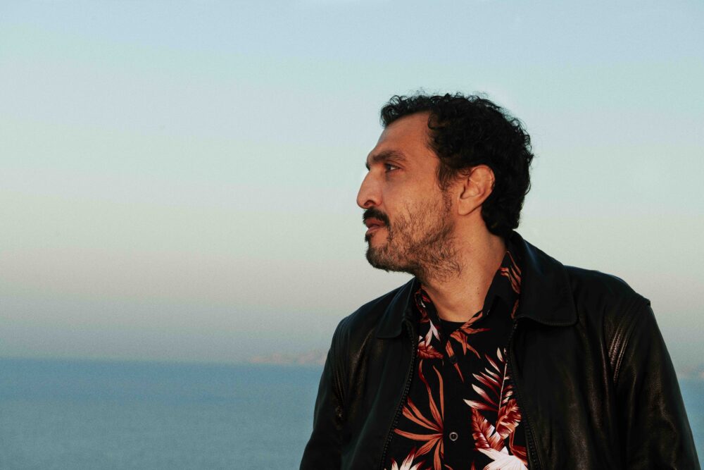 Portrait d'un homme de profil regardant au loin, on voit la mer derrière lui