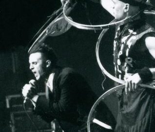 Photo noir et blanc d'un chanteur criant dans le micro et d'un artiste jonglant avec des cerceaux