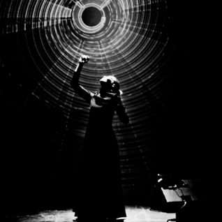 Photo noir et blanc de style clair obscur montrant une femme qui tend la main vers une lumière tournante