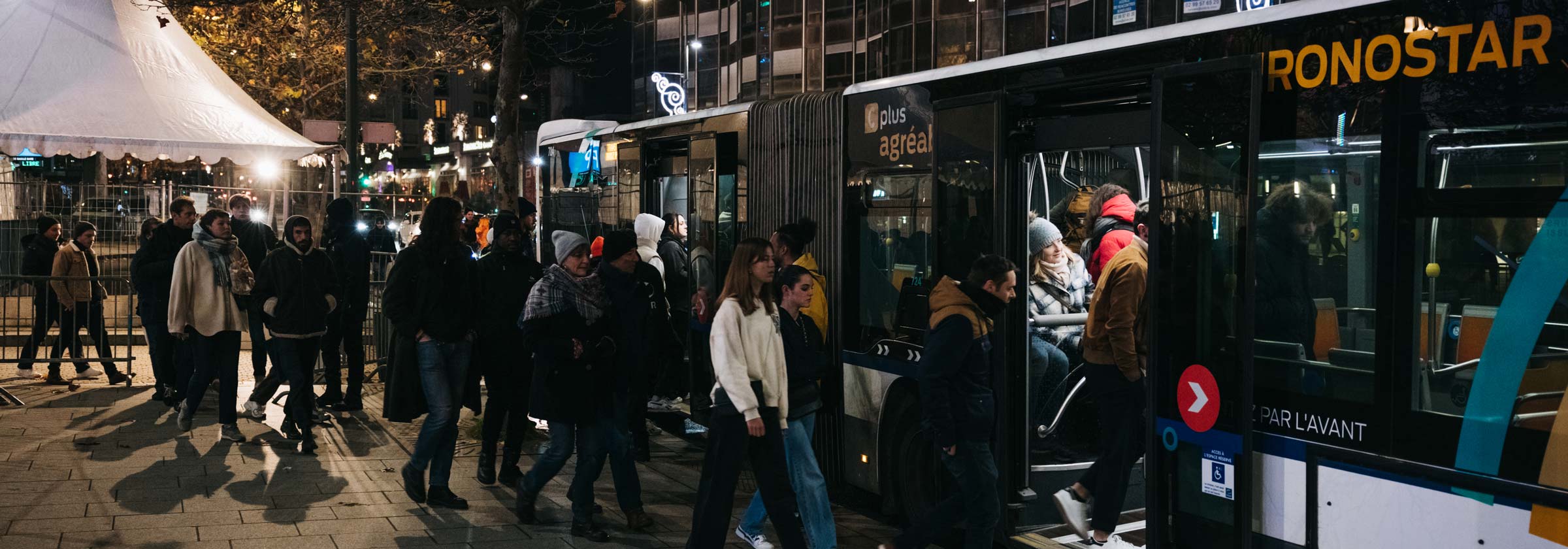 Photo de nuit avec plusieurs personnes qui montent dans un bus