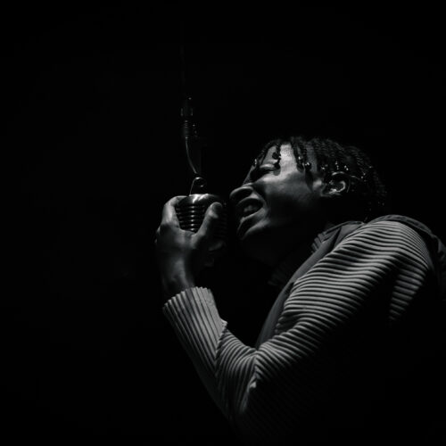 Photo en noir et blanc d'un artiste chantant dans un micro rétro