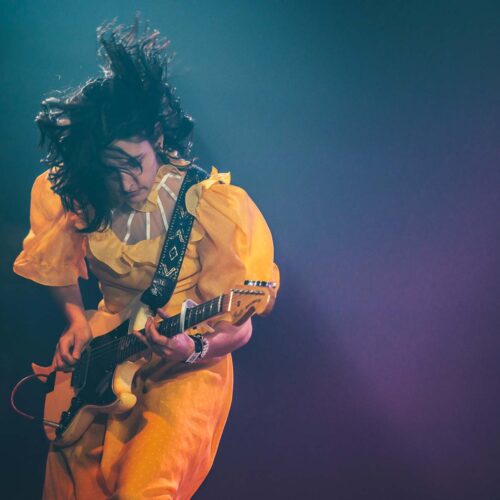 Une guitariste en robe jaune romantique joue les cheveux en mouvement