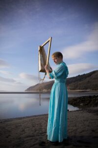 une femme joue de la harpe sur la plage