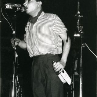 Photo en noir et blanc d'un chanteur tenant une bouteille à la main
