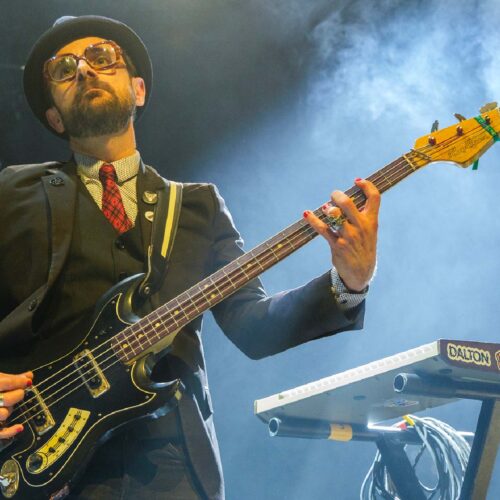 un bassiste avec costume chapeau et lunettes