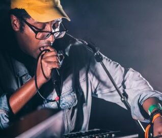 Un artiste manipule une console son en même temps qu'il chante