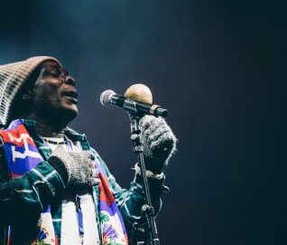 Un artiste avec gant bonnet écharpe chante devant le micro