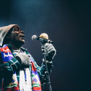 Un artiste avec gant bonnet écharpe chante devant le micro