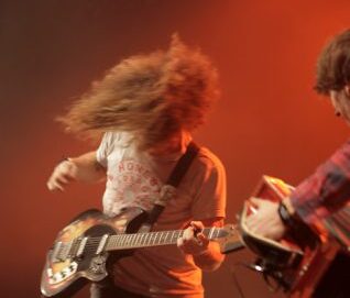 Photo d'un guitariste en action avec cheveux longs en mouvement