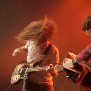 Photo d'un guitariste en action avec cheveux longs en mouvement